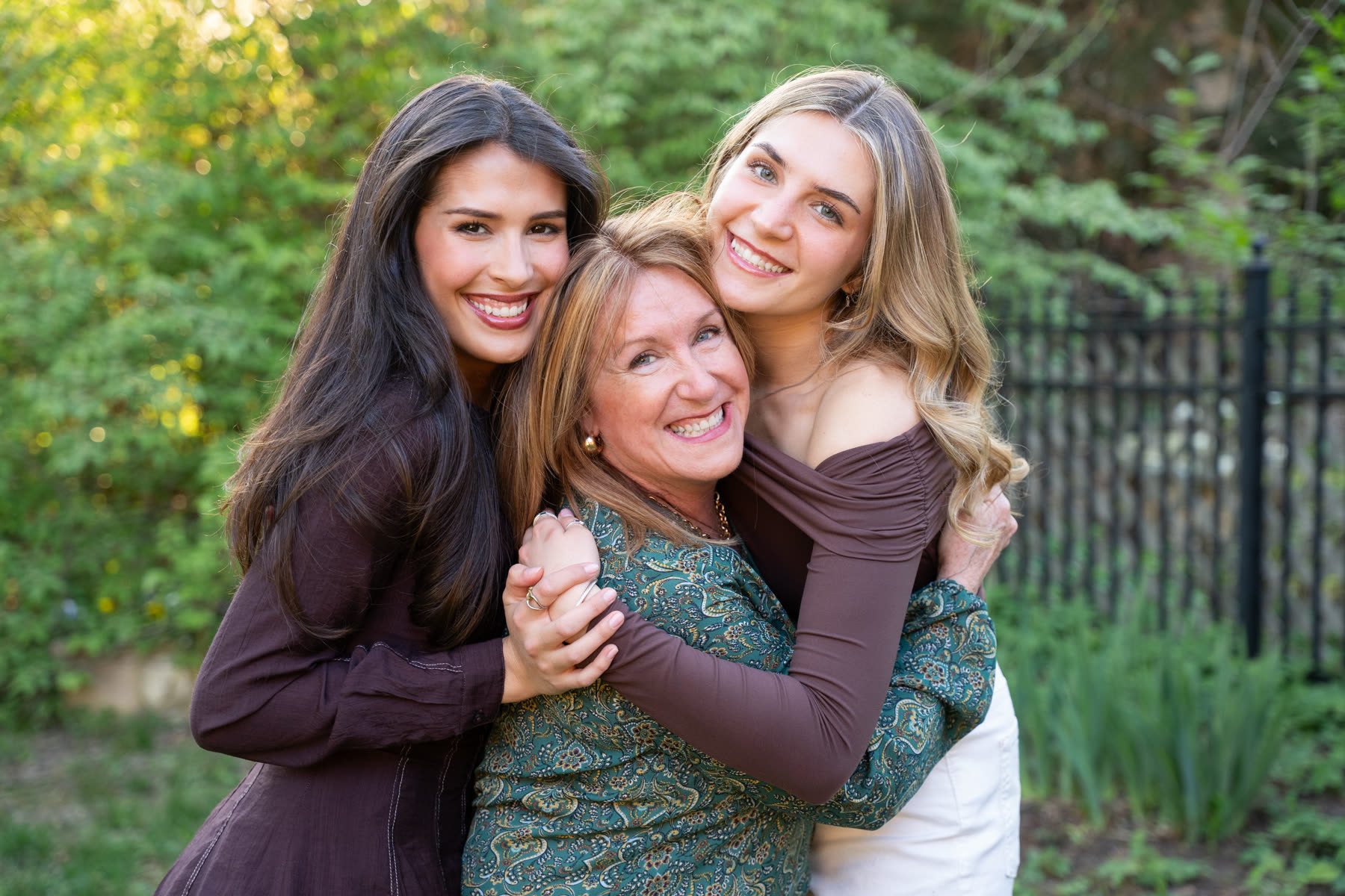 Carolyn Lorente smiling with two young women in a backyard setting.